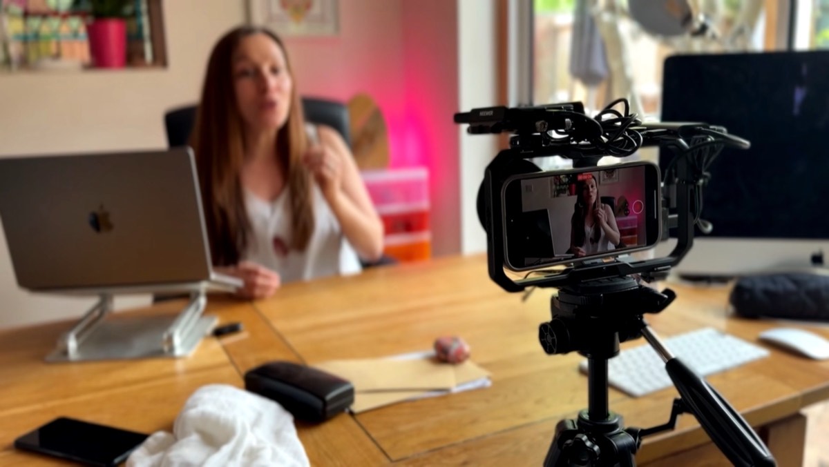 A live show being filmed at Cordelia's desk, camera and phone rig in the foreground